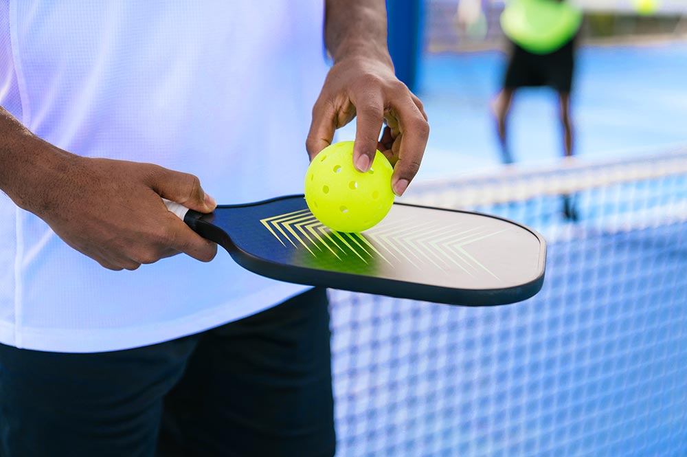 Man Holding A Pickleball Paddle And Ball